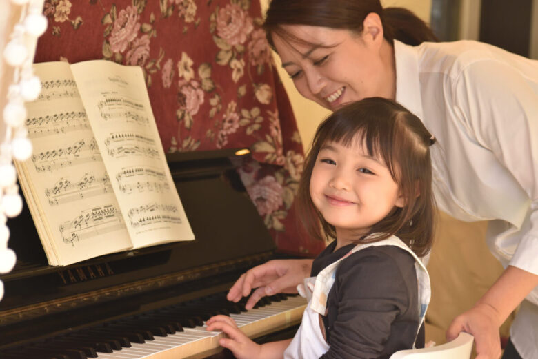 お母さんと一緒にピアノを練習する女の子の写真